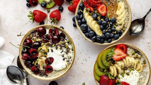Three bowls of oats with fruit, berries and yoghurt.