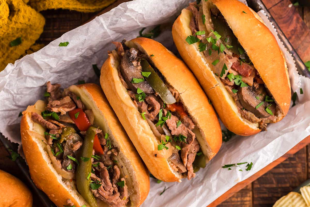 Philly cheesesteak sandwiches with bacon in a tray.