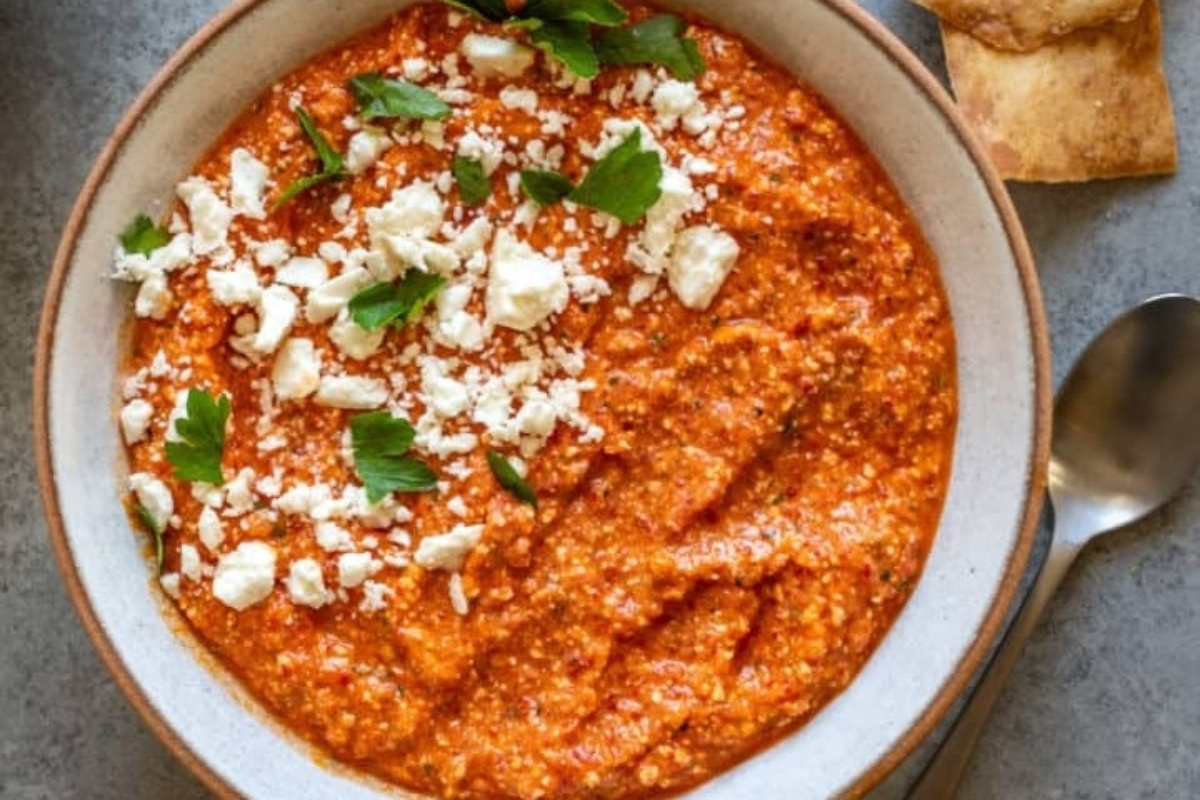A bowl of hummus with feta cheese and pita bread.