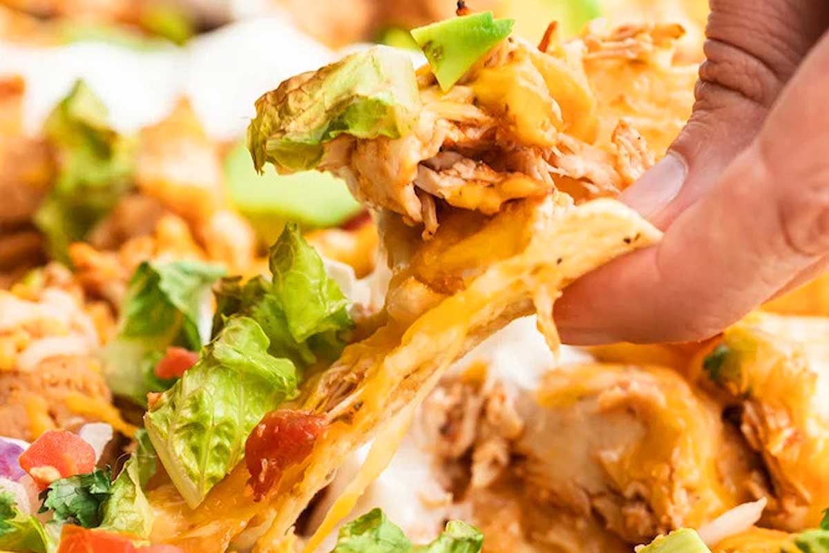 Nachos with shredded chicken and colorful toppings.