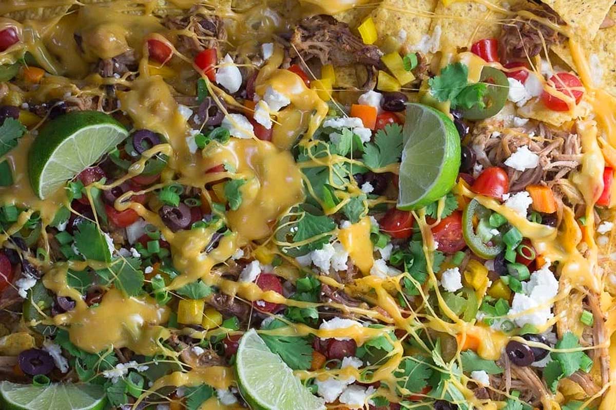 Colorful shredded pork nachos with cheese and vegetables.