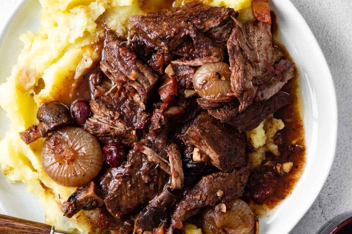 A plate with beef and mashed potatoes.