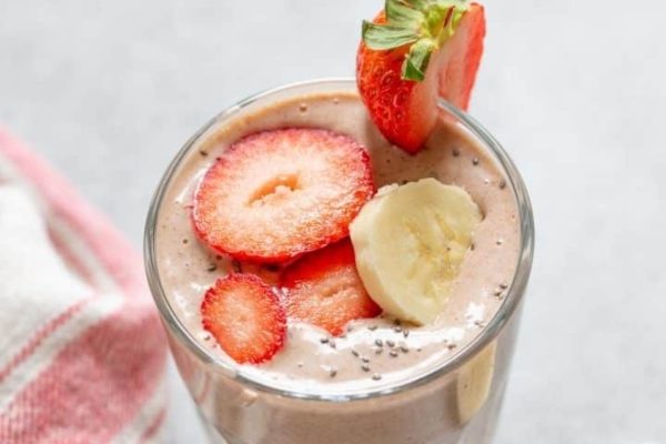 Strawberry banana peanut butter smoothie topped with strawberry and banana slices on top. 