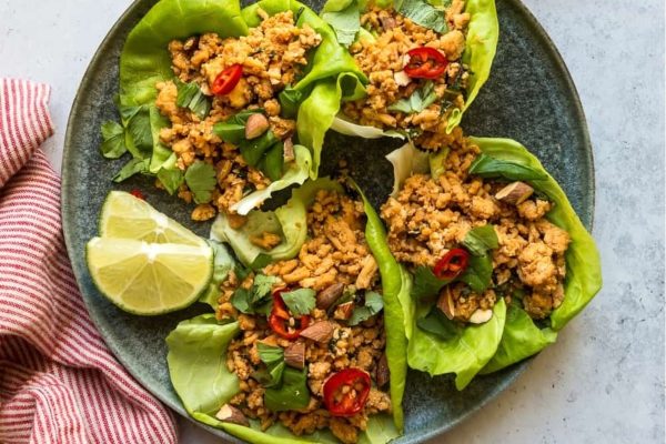 Lettuce wraps filled with thai basil chicken, red pepper slices and fresh herbs.