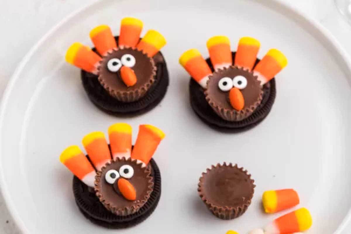 Turkey cookies with candy corn on a white plate.
