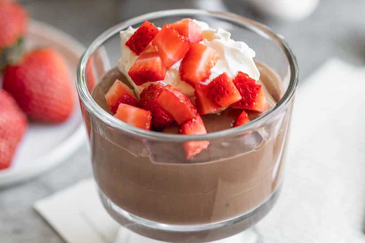 Chocolate pudding in a glass dish with strawberries on top.