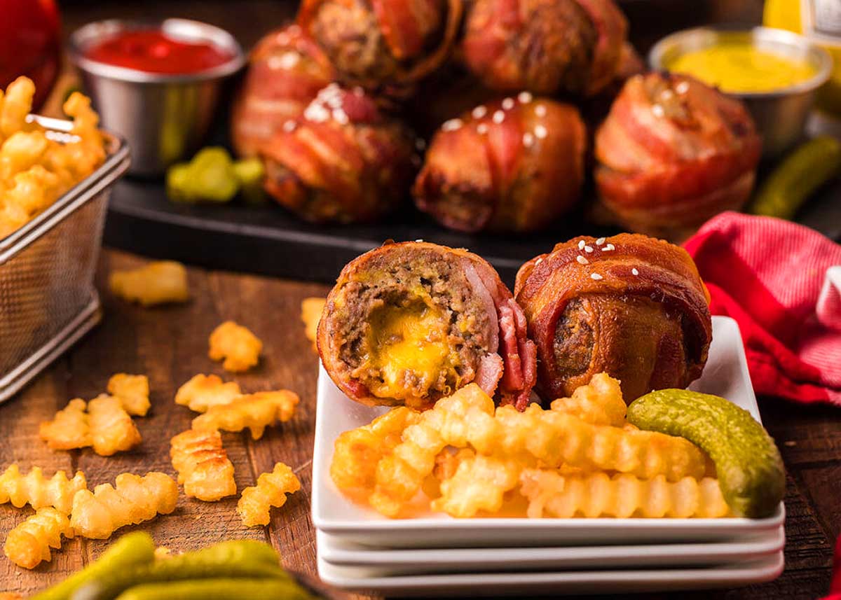Bacon wrapped cheese burger bits on a plate with fries. This is one of the best bacon recipes.