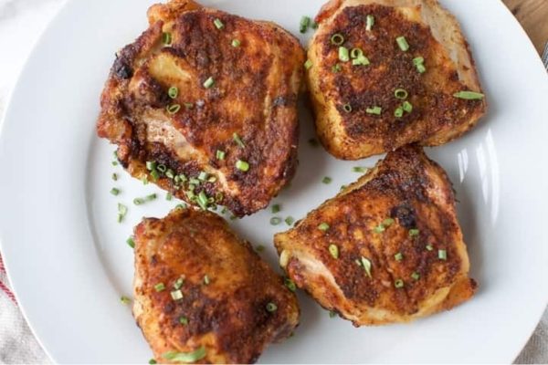 Air fryer chicken thighs on a white plate.