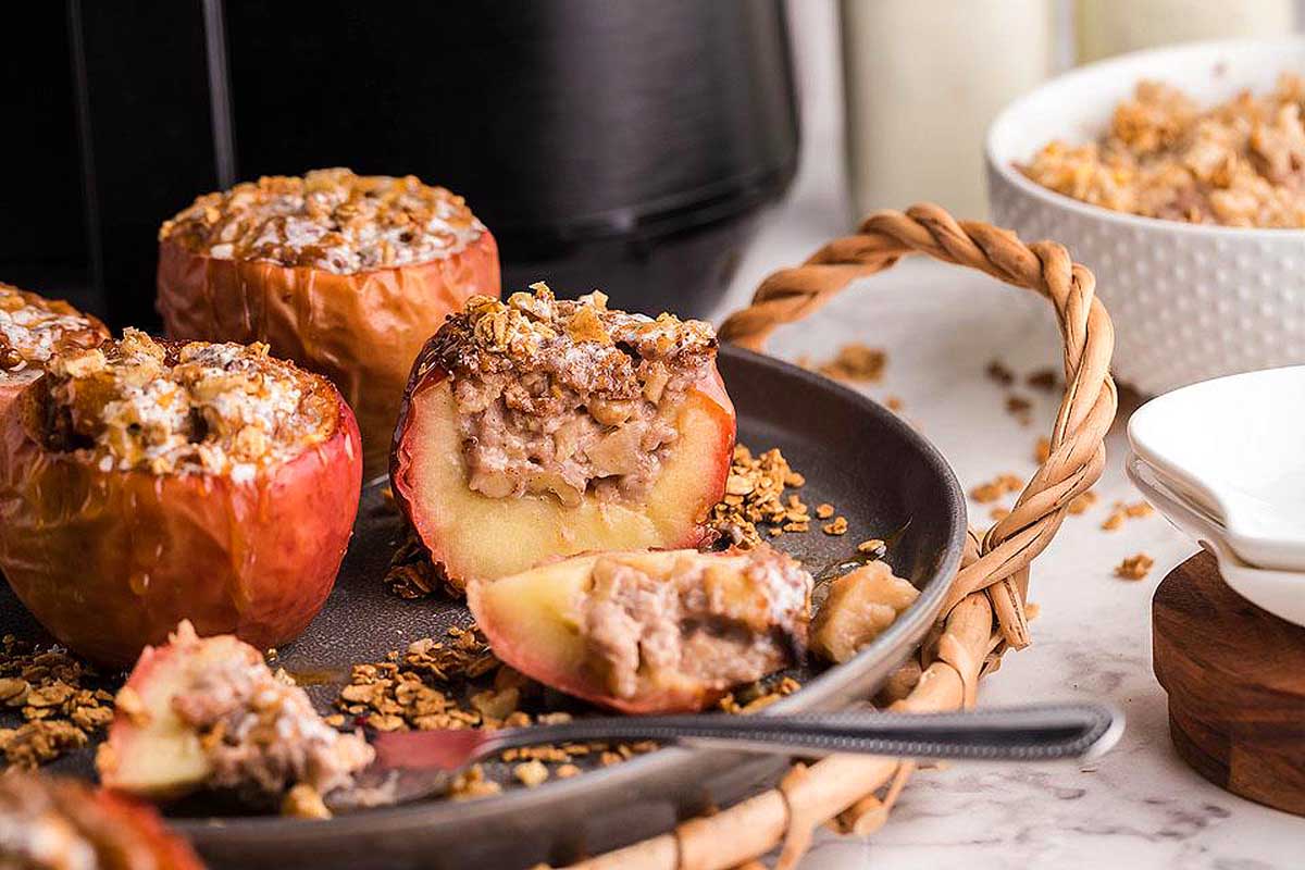 Cinnamon baked apples on a dark plate with spoon.