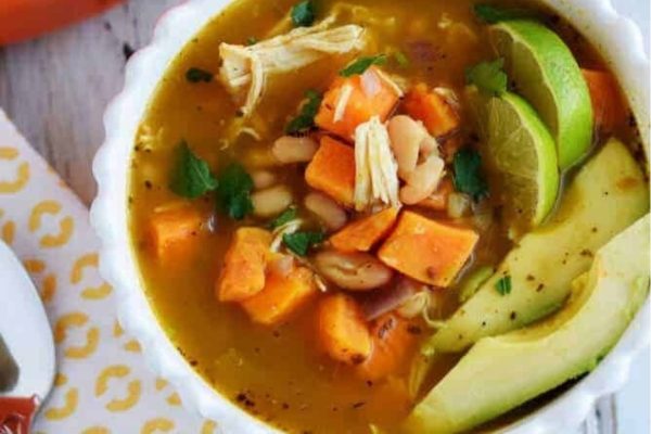 A bowl of chicken chili soup with avocado.