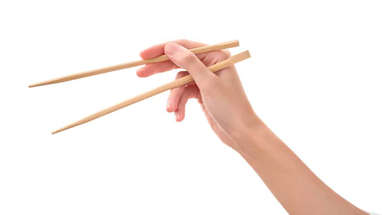 A hand holding chopsticks.