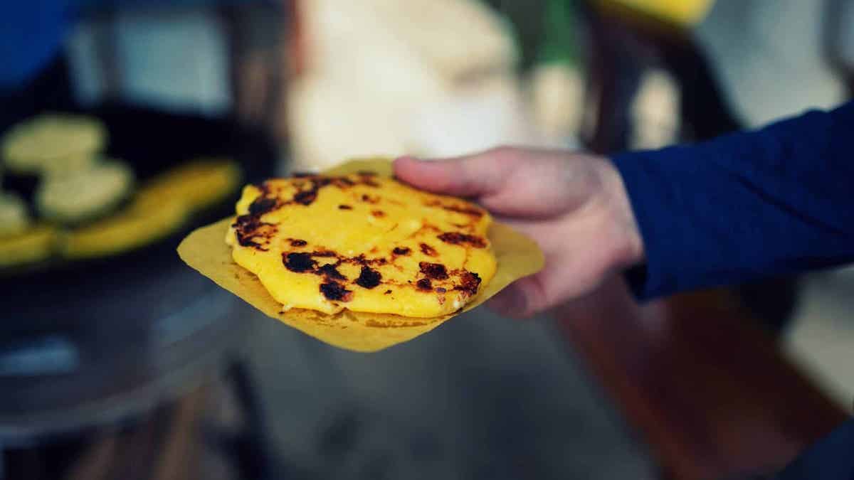 Hand holding a fresh arepa (south american street food).
