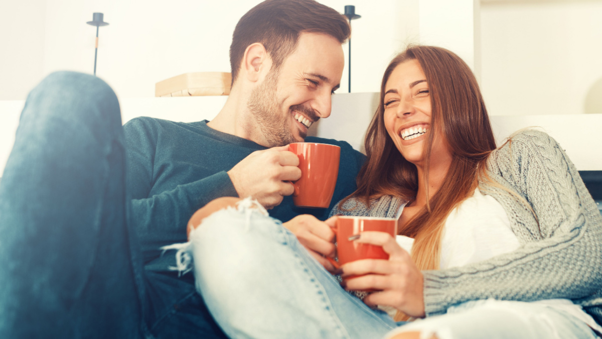Cheerful young couple in the morning at home drinking coffee.