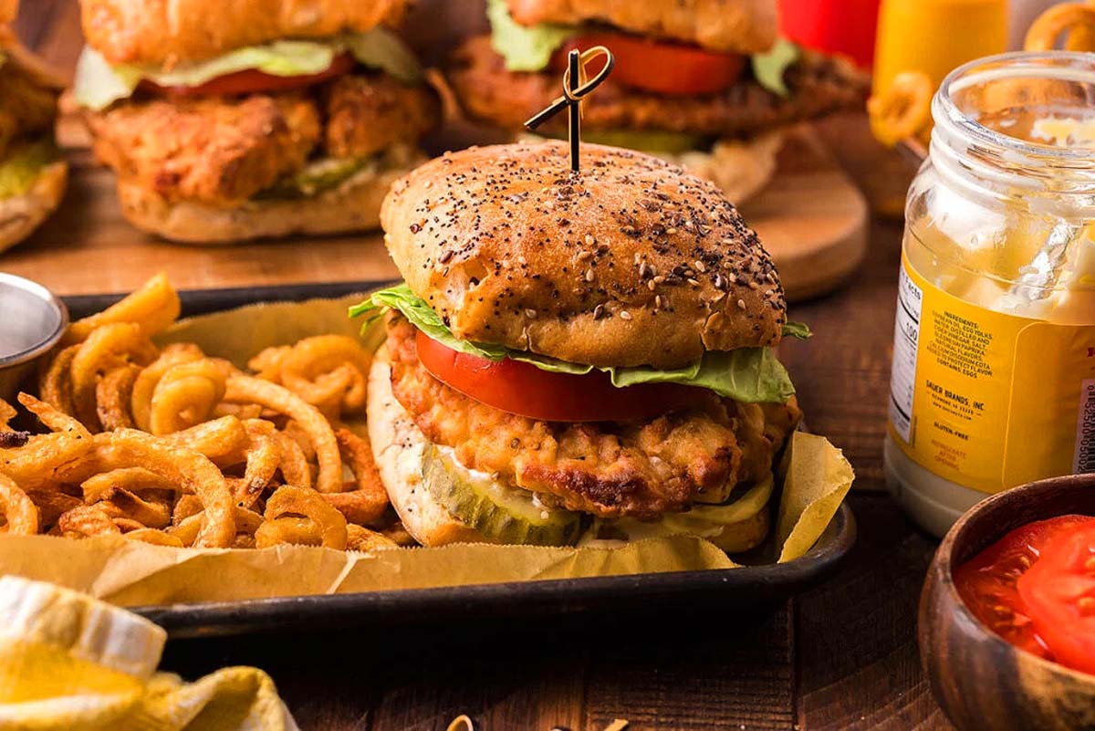 A fried chicken sandwich in a tray with french fries.