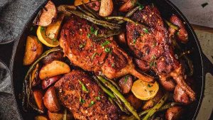 Grilled pork chop recipe in a skillet with potatoes.