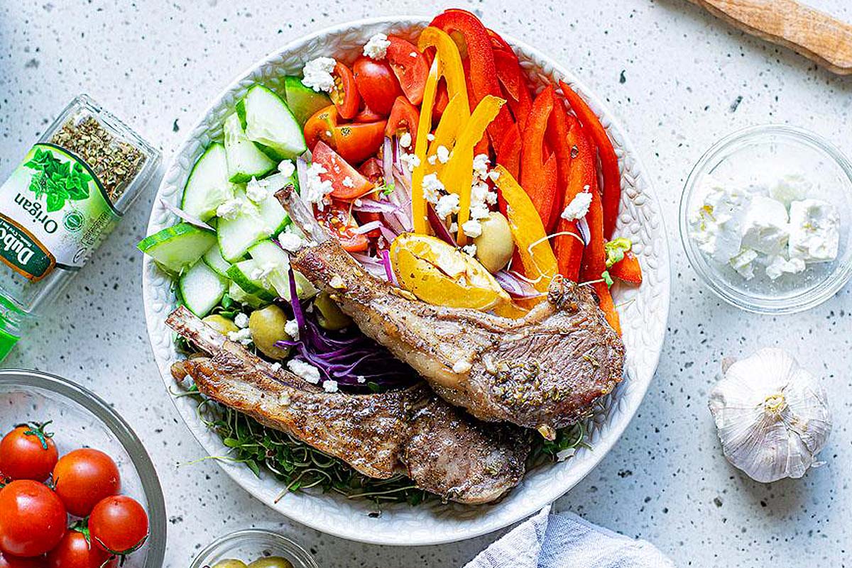 Greek pork chops on a plate with fresh vegetables.