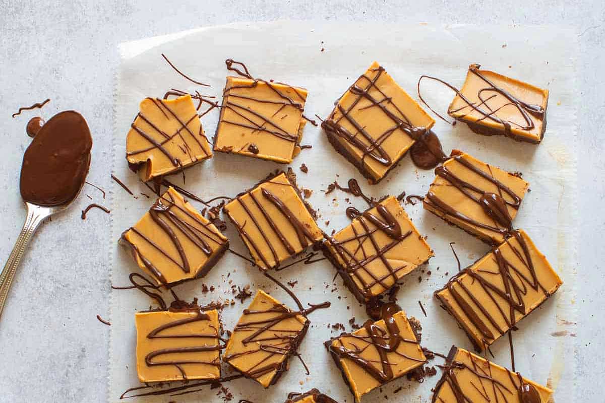 Peanut butter fudge with chocolate drizzle on parchment paper.