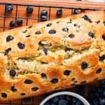 A delicious loaf of blueberry bread cooling on a rack.