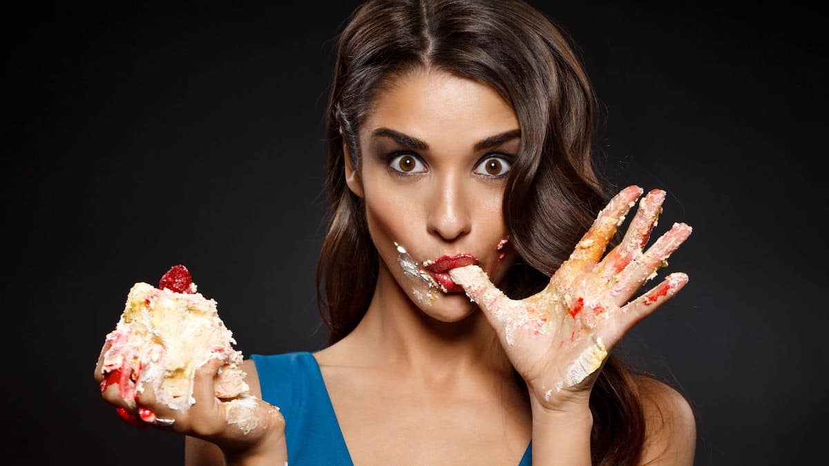 Woman eating cake with her hands.