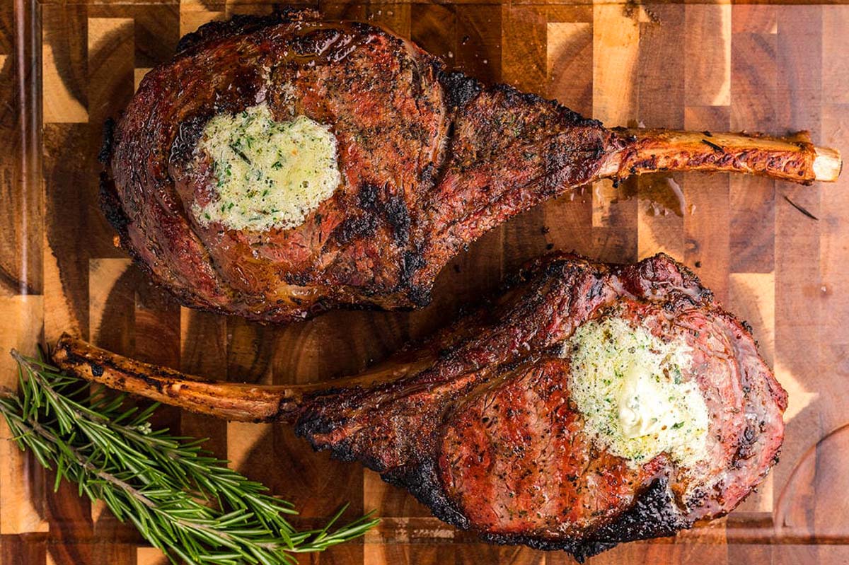 Overhead view of two tomahawk steaks on a cutting board. 
