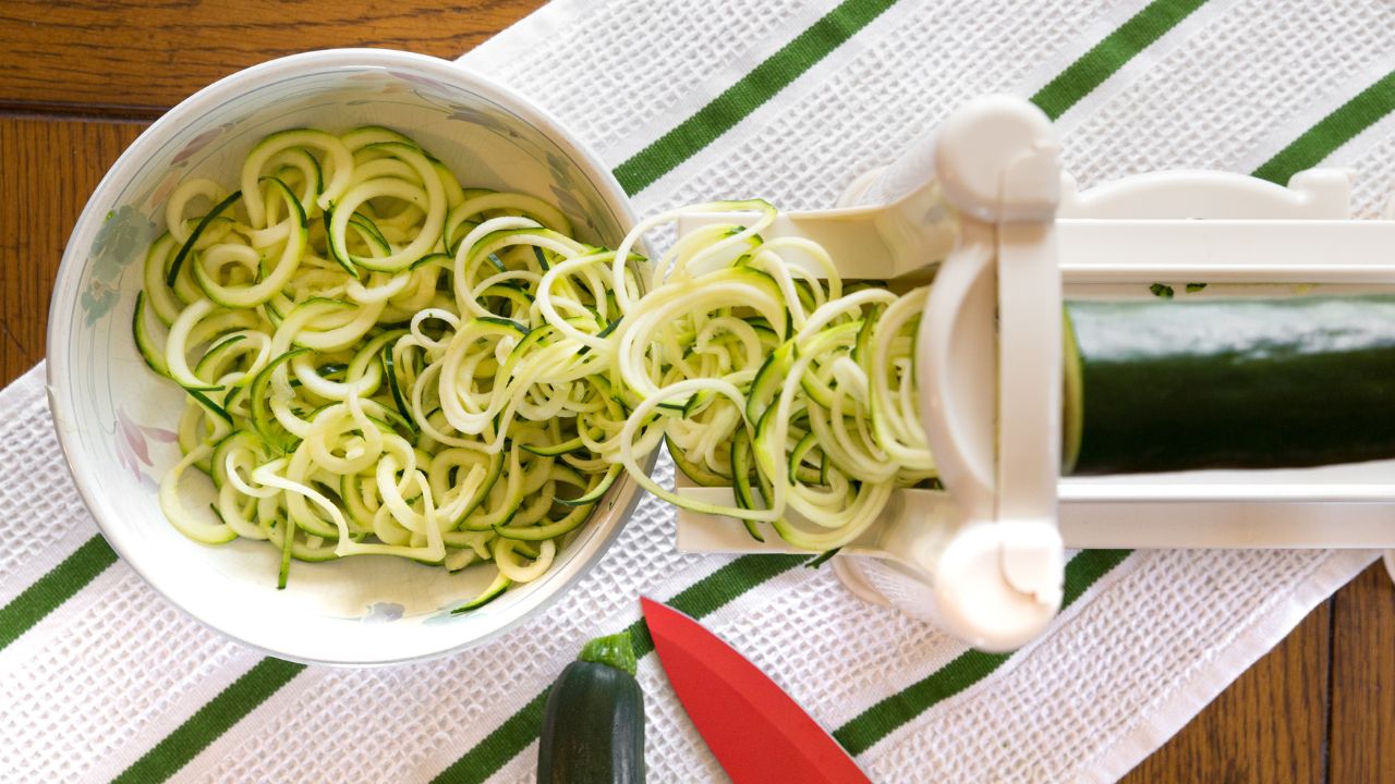 Zucchini being fed through a spiralizer tube to make spiral zucchini zoodles. 