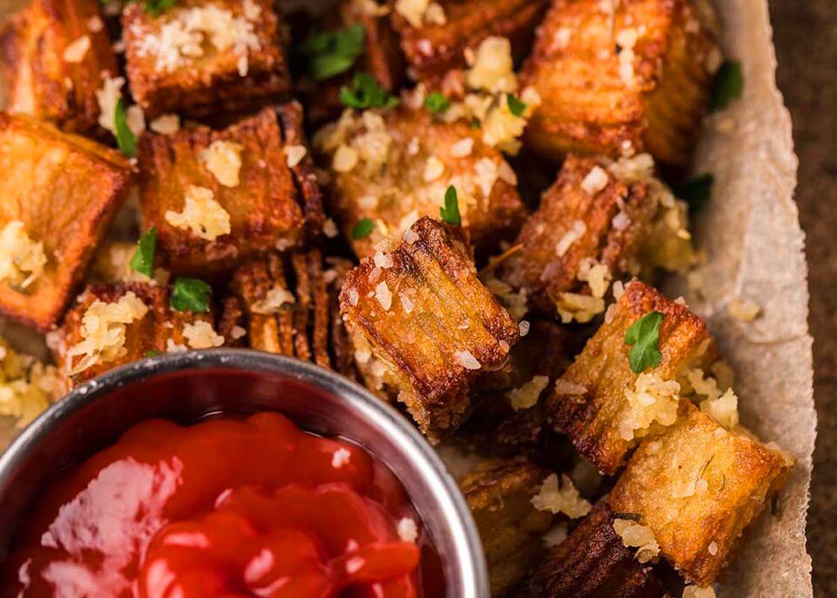 Crispy Stacked Potatoes on a cutting board with ketchup on the side.