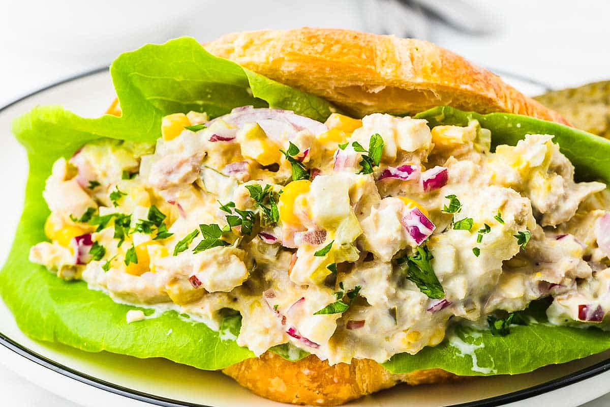 A thick tuna salad sandwich served on a croissant.