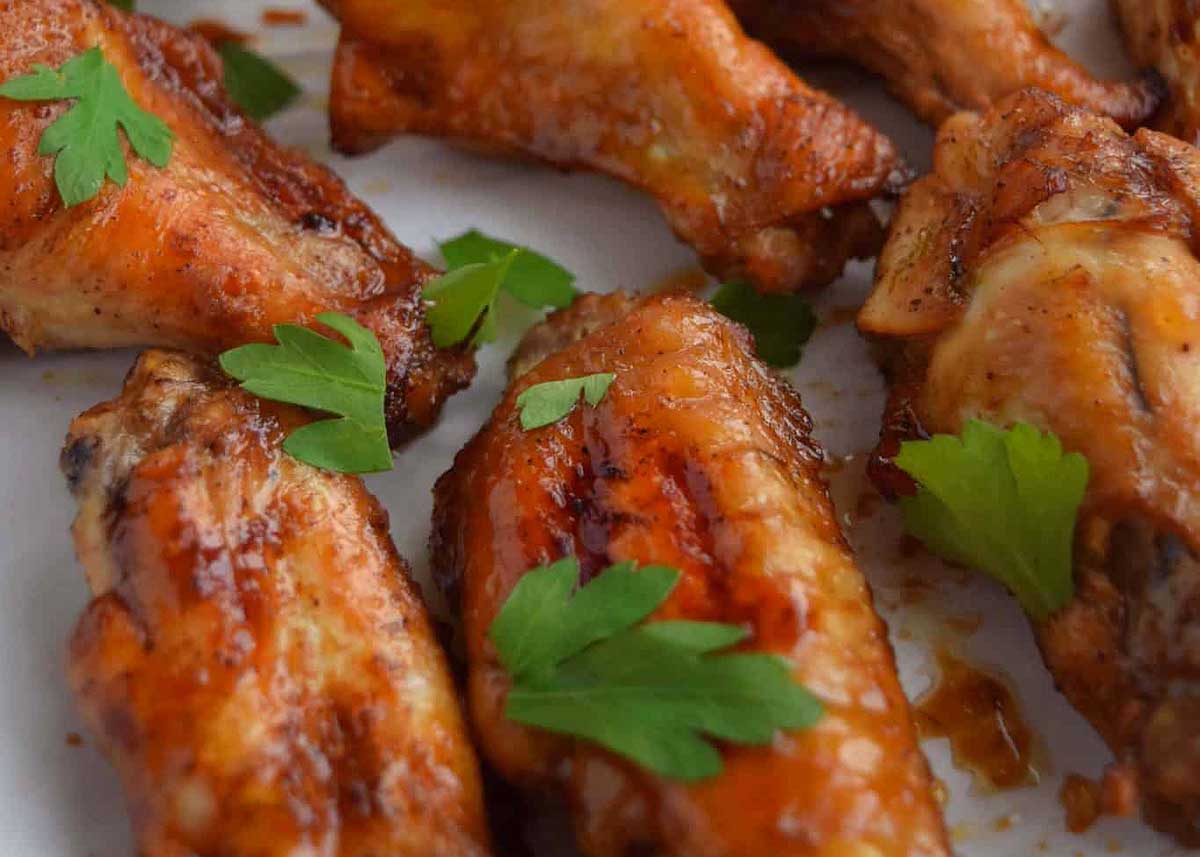 Chicken wings on a platter garnished with chopped herbs.