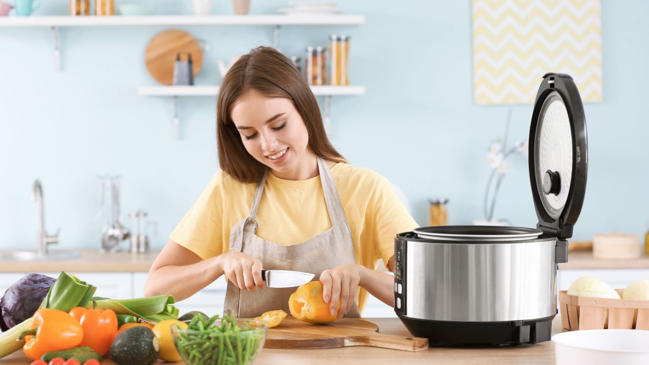 Woman cutting vegetables for stewing in multi cooker.