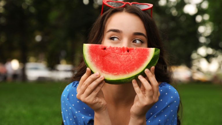 Young woman with watermelon in a park.