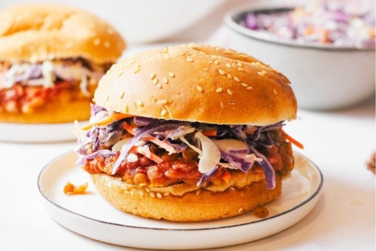 Bbq chicken burgers with coleslaw on a white plate served on a bun.