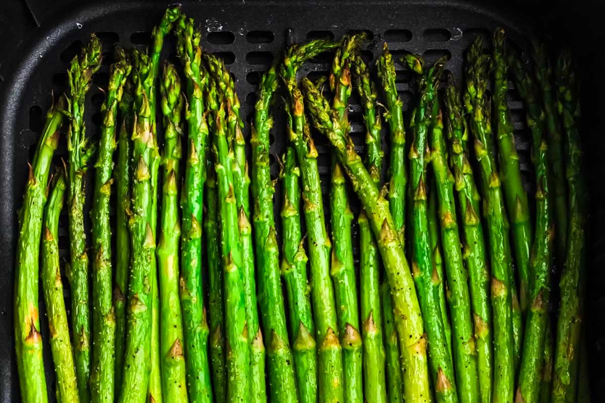 A close up of green asparagus in an air fryer for Thanksgiving.
