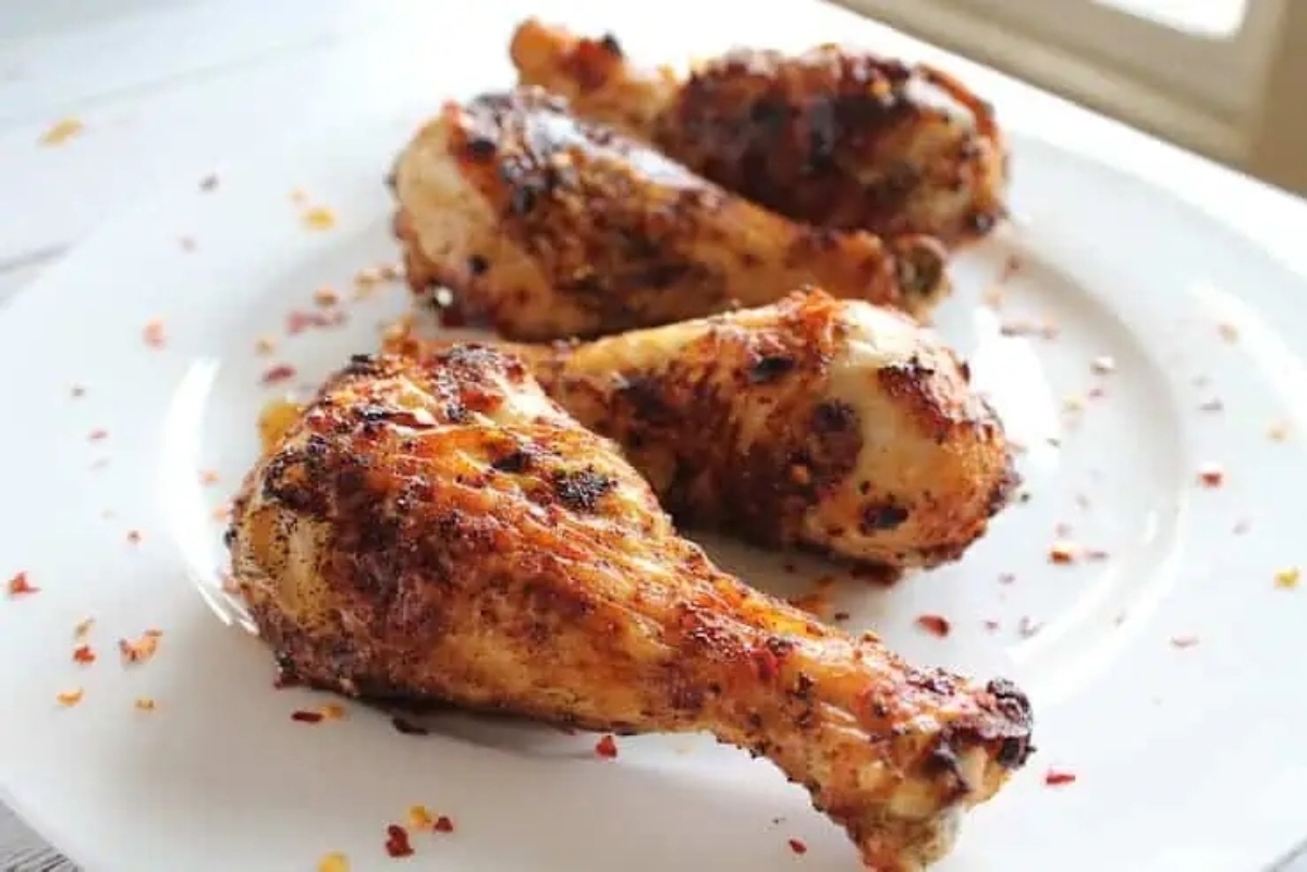 A plate of grilled chicken legs on a wooden table, perfect for winter recipes.