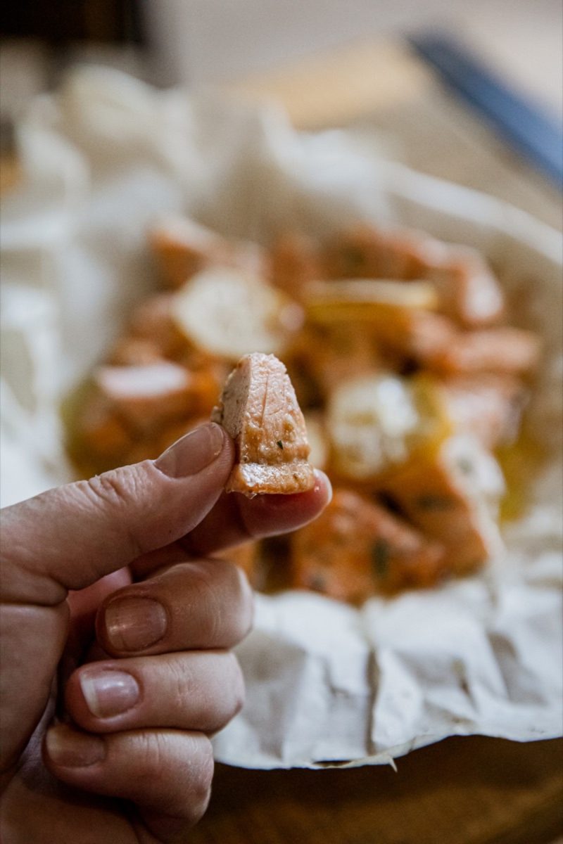 A person holding air fryer salmon bites on a piece of paper.