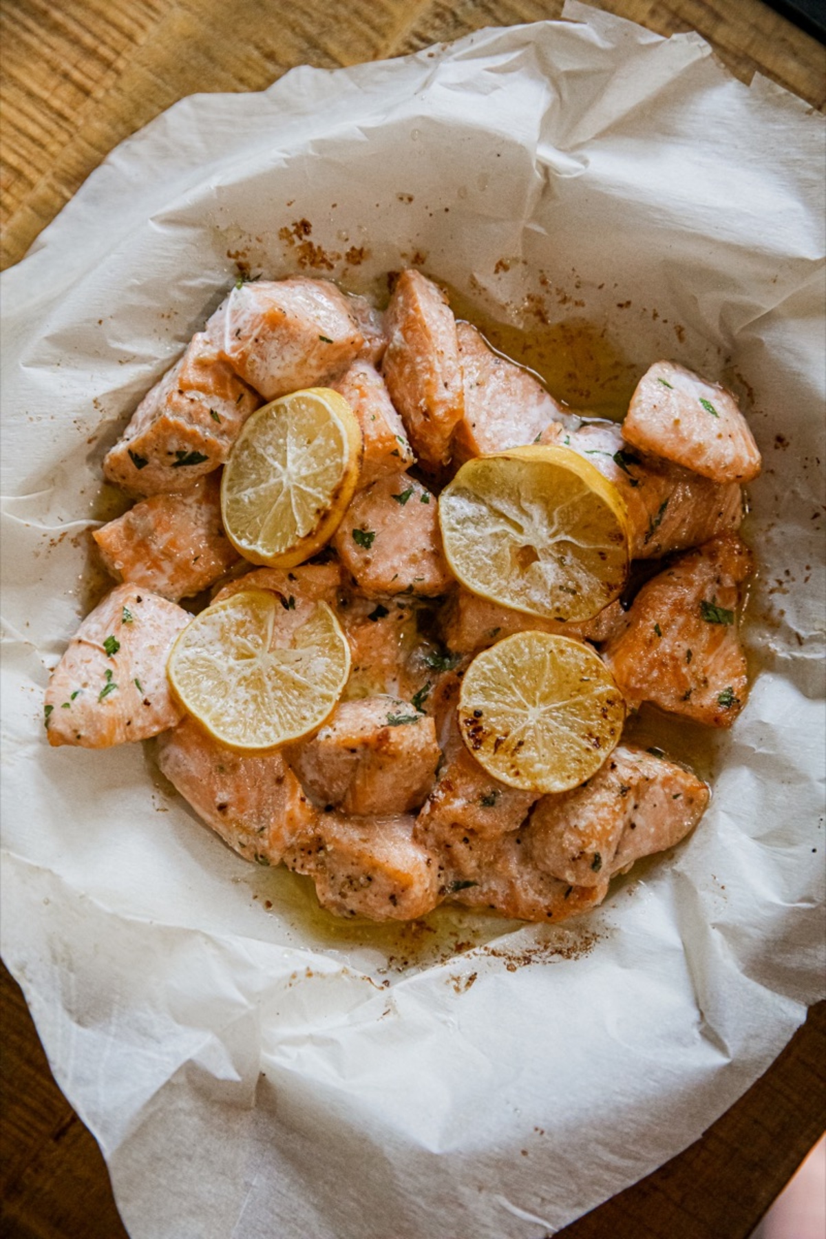 Air fryer salmon bites in a paper bag with lemon slices.