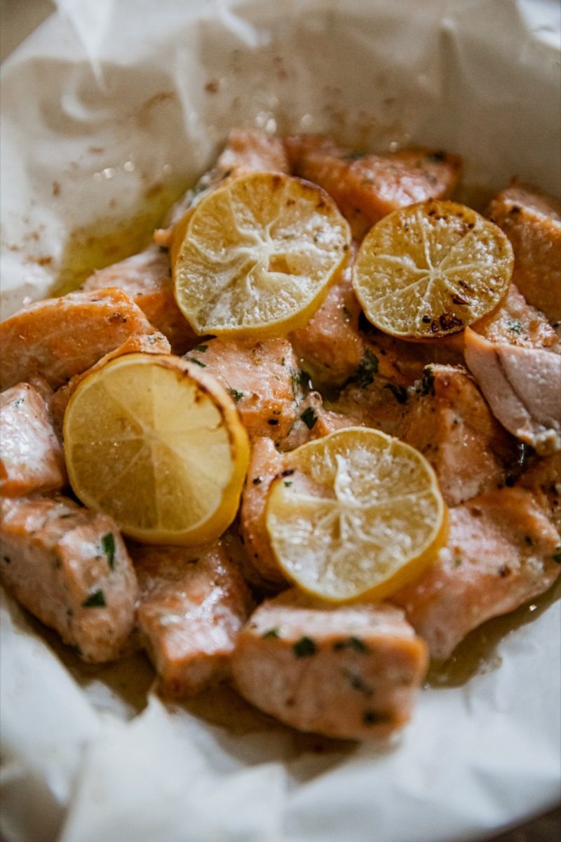 Air fryer salmon bites served with lemon slices on a sheet of paper.