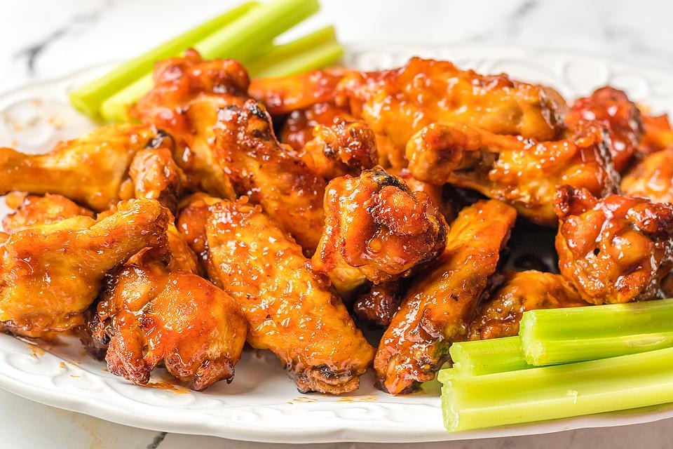 Game Day favorite - crispy chicken wings served on a plate alongside celery sticks.