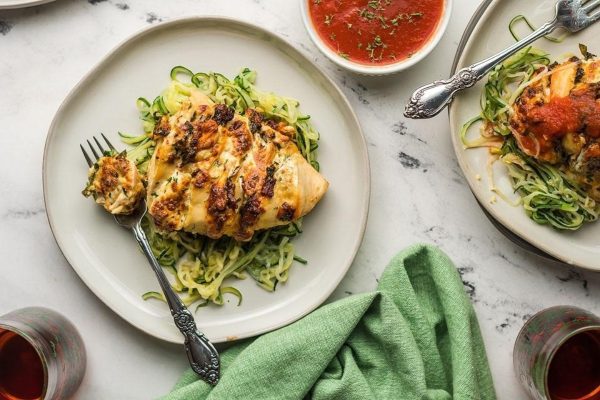 Two plates with grilled chicken and zucchini noodles.