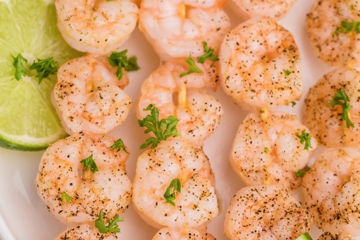 Shrimp skewers on a plate with lime wedges, perfect for a Feast.