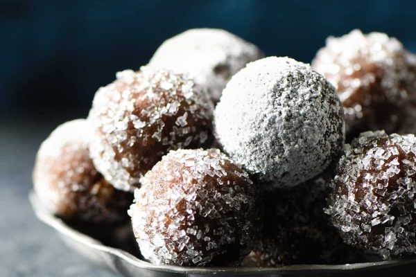 A silver bowl filled with sugared doughnuts.
