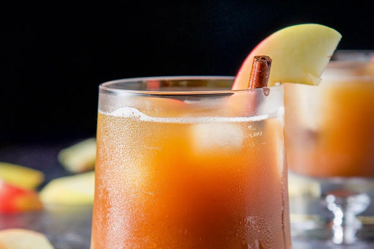 A festive Thanksgiving cocktail featuring a glass of apple cider garnished with cinnamon sticks and apples.