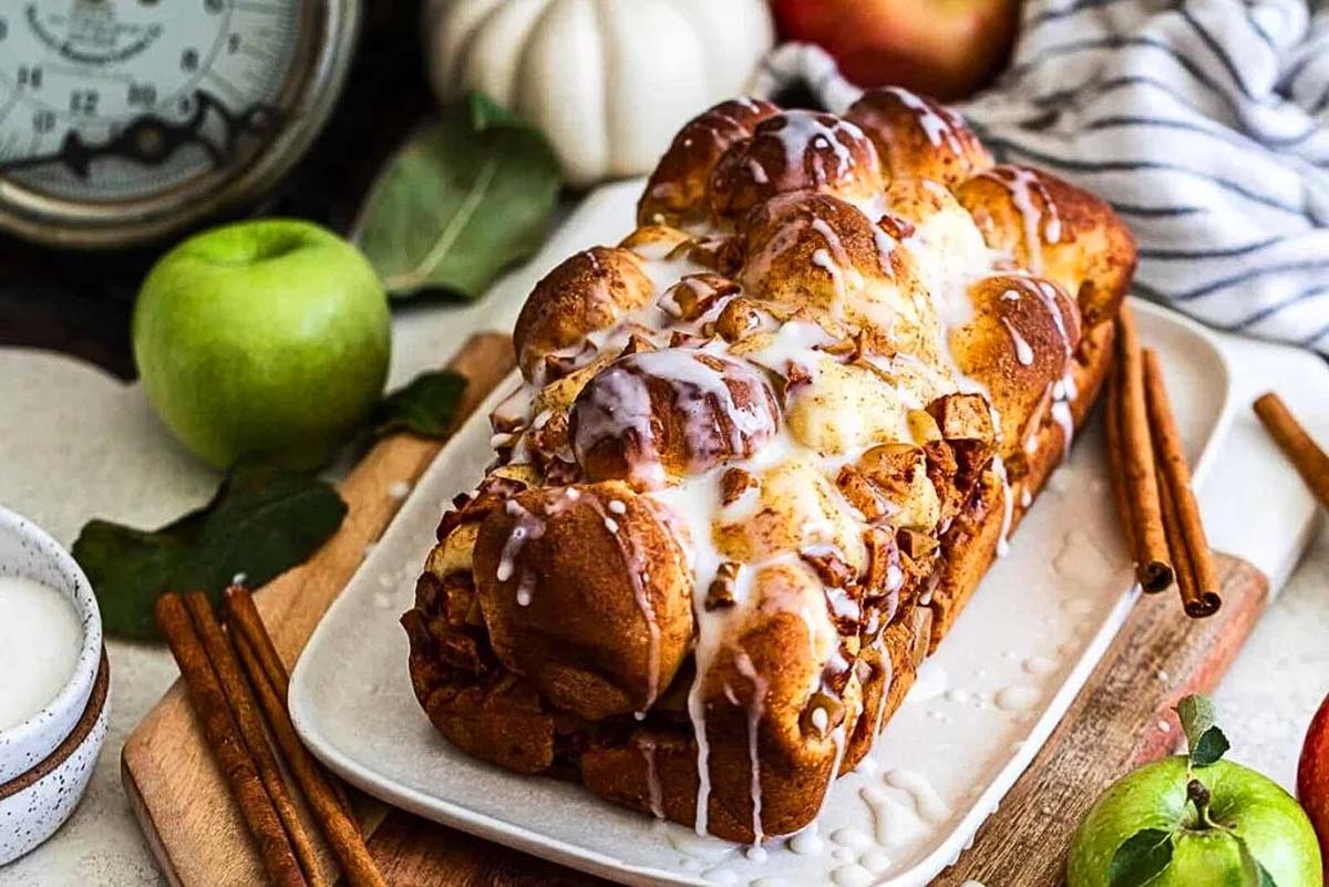 Apple cinnamon bread on a plate with apples and cinnamon, perfect for apple cider recipes.