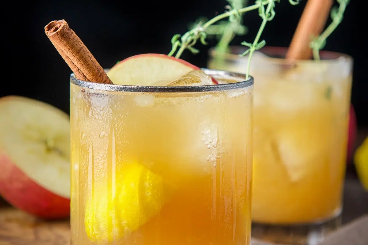 A tantalizing recipe featuring apple cider garnished with cinnamon sticks and apples.