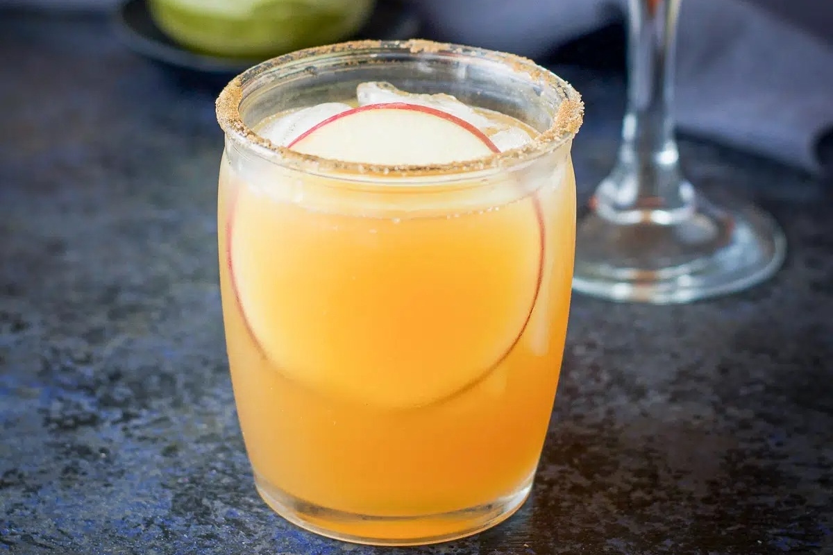 An inviting glass of apple cider garnished with a fresh slice of apple.