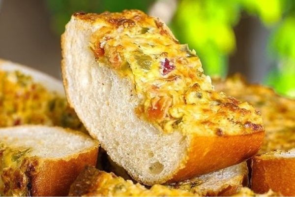 A slice of bread with cheese and vegetables on it.