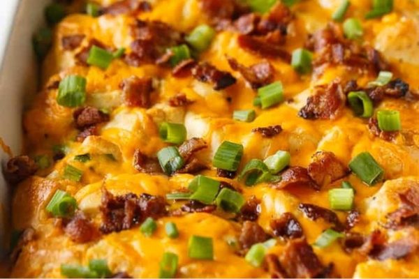 A casserole dish with cheese, bacon and green onions.