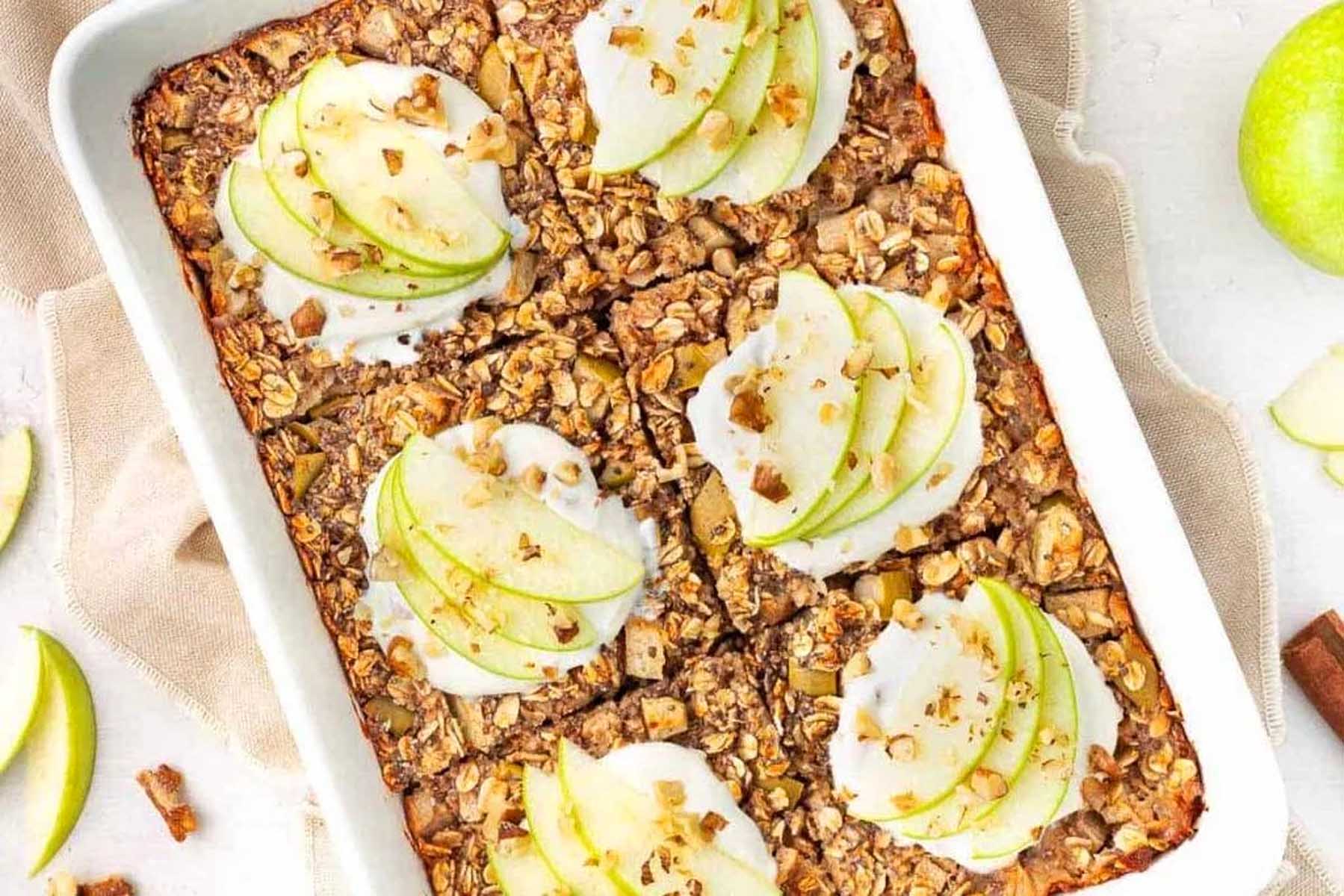 A white baking dish with apples and granola.