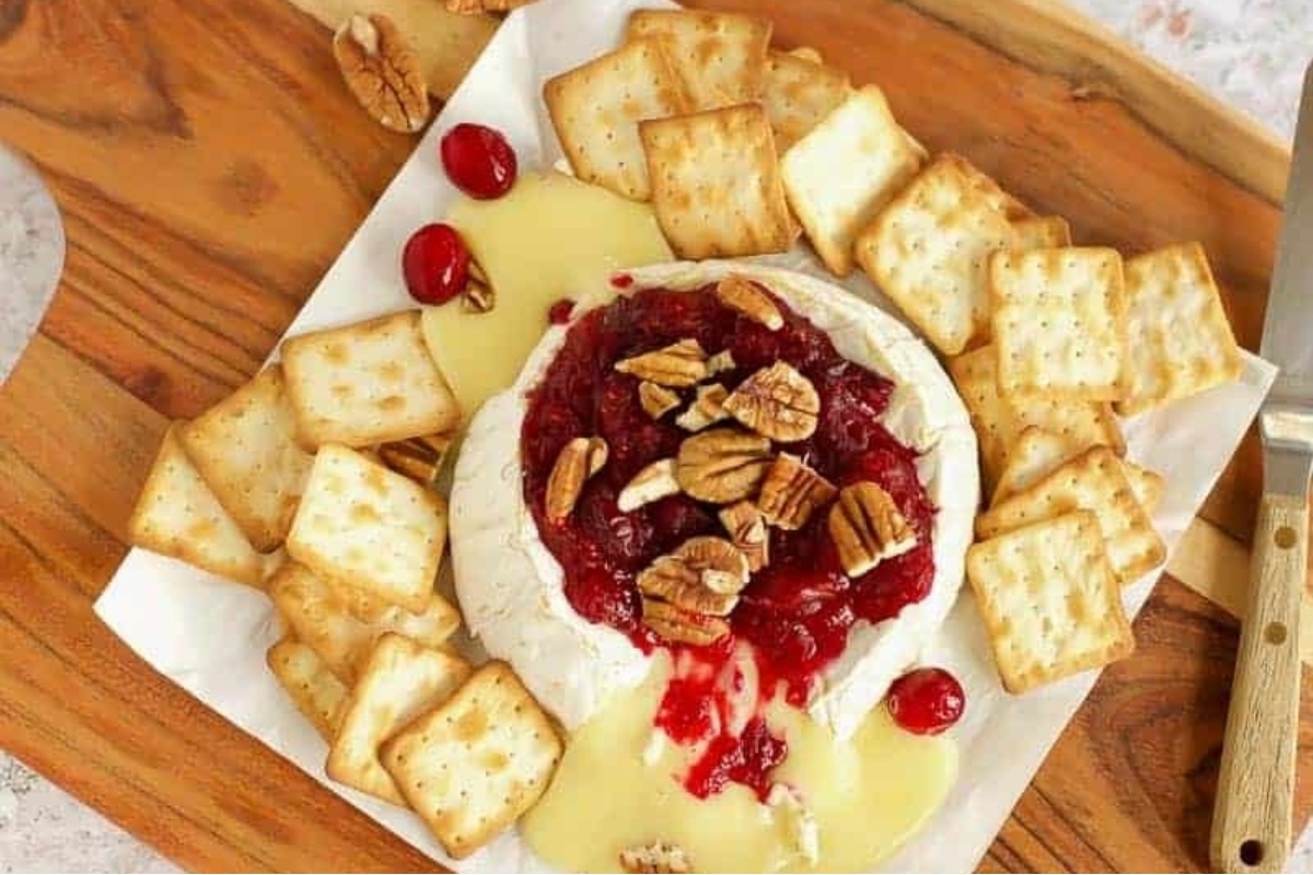 A festive Christmas cheese platter, complete with a delightful array of appetizers such as crackers and cranberry sauce, perfect for any holiday party.