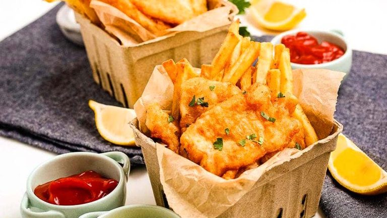 Pub-style fried fish served in paper baskets with ketchup and lemon wedges.