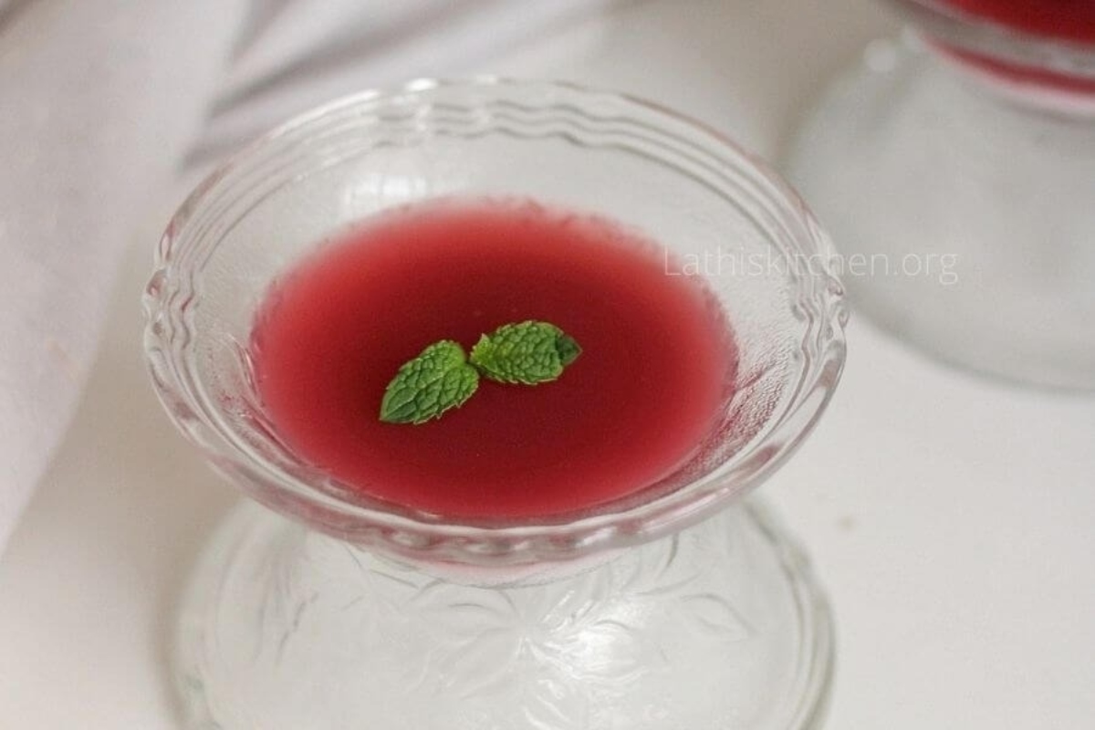 Two glasses of pomegranate juice with a mint leaf on top.